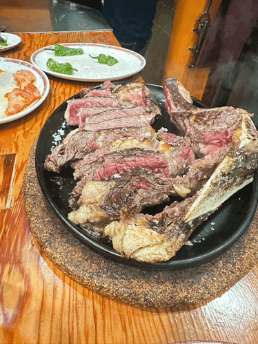a large piece of meat is on a black plate on a table