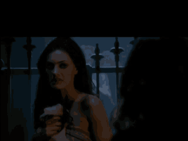 a woman with her mouth open is standing next to a man in a dark room
