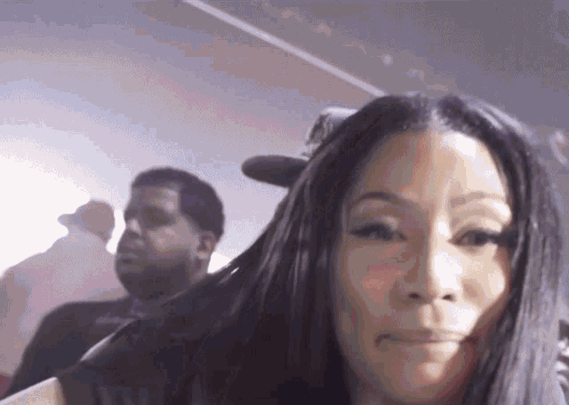 a woman taking a picture with a man behind her