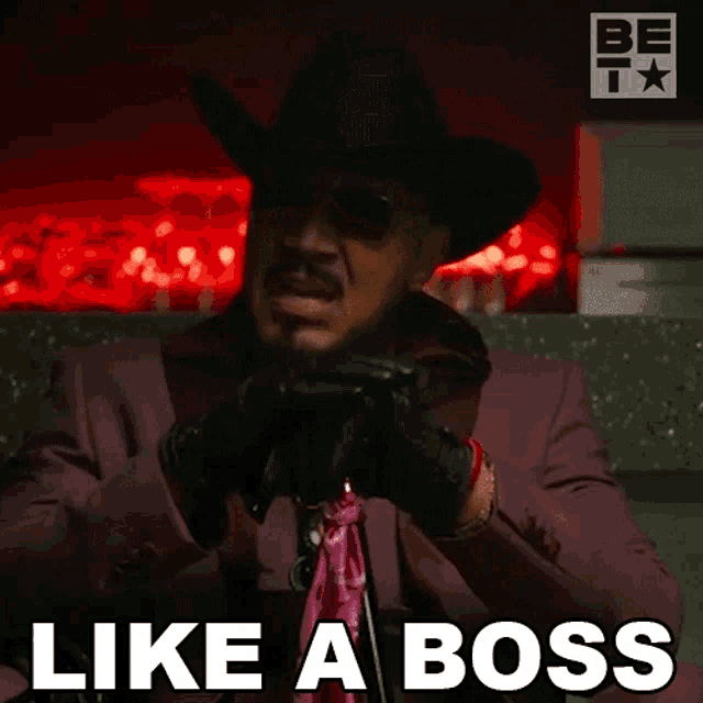 a man in a purple suit and cowboy hat says like a boss