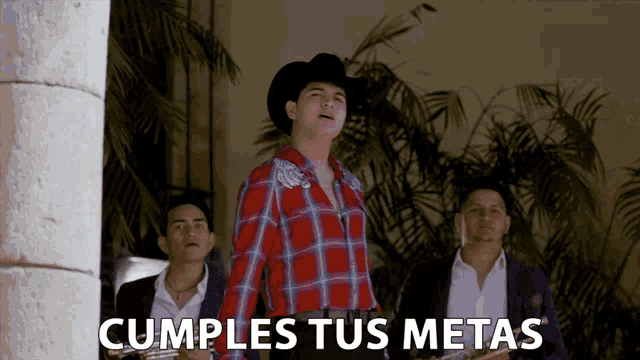 a man in a cowboy hat is standing in front of a sign that says cumples tus meta