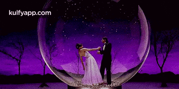 a man and a woman are dancing inside of a glass ball .