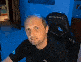 a man with a bald head is sitting in a gaming chair .