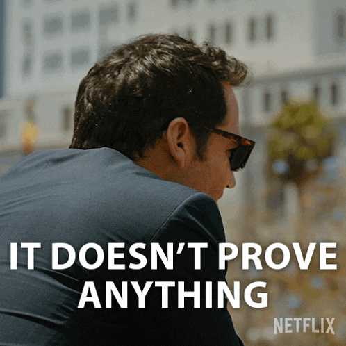 a man wearing sunglasses and a suit has the words " it does n't prove anything " on his back