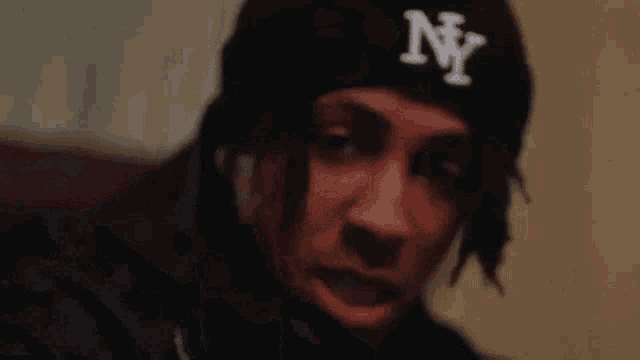 a close up of a person wearing a ny hat .