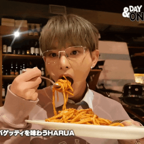 a person with glasses is eating spaghetti from a plate that says day & on
