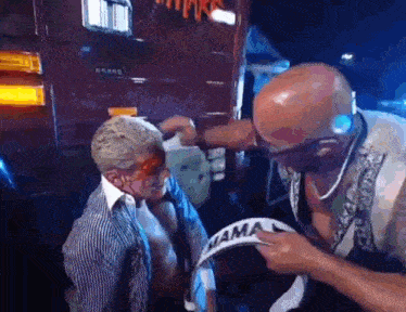 a man is putting a bandage on another man 's head while wearing headphones .