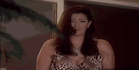 a woman in a leopard print dress and necklace is standing in a room .