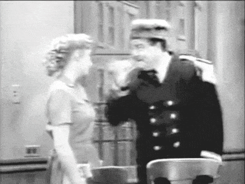 a black and white photo of a man and woman talking to each other