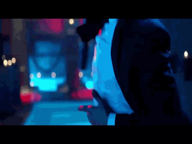 a man in a suit and tie is holding a gun in a dark room