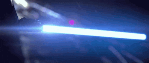 a person is holding a blue light saber in their hand in the dark .