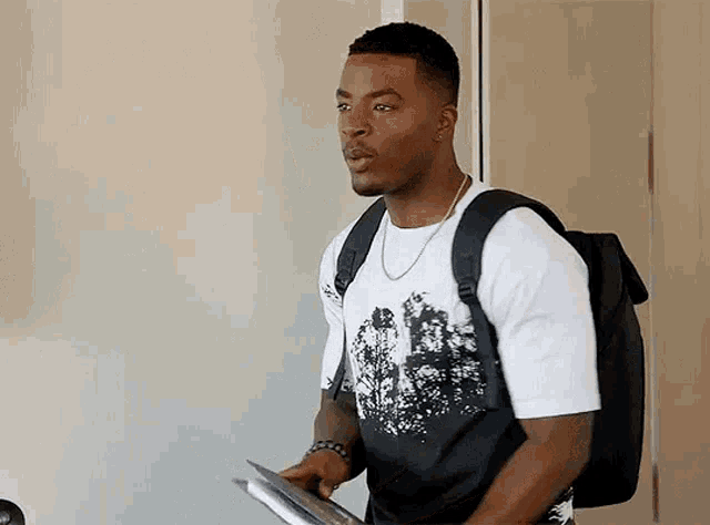 a man wearing a backpack and a white shirt is holding a piece of paper .