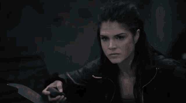 a woman in a black jacket is holding a black object