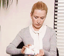 a woman in a grey sweater and white scarf is holding a bottle of pills