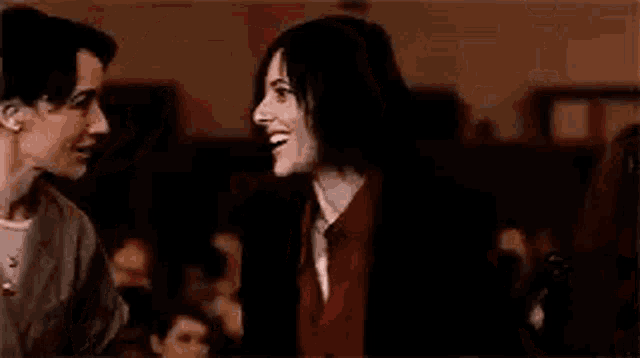 two women are whispering into each other 's ears in a dark room .