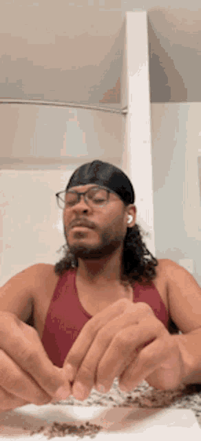 a man wearing glasses and a headband rolls a cigarette
