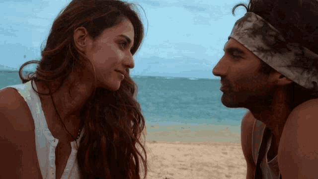 a man and woman are looking at each other on a beach