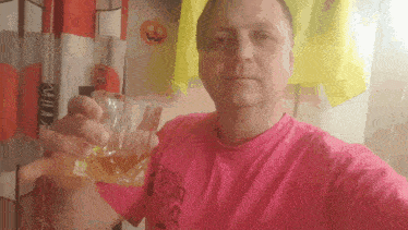 a man in a pink shirt is holding a glass of beer