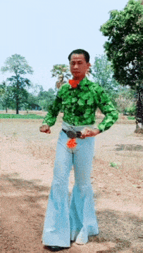 a man wearing a green shirt and blue pants is holding a flower
