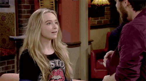 a woman wearing a rolling stones t-shirt talks to a man