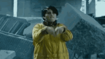 a young man in a yellow jacket is making a middle finger sign .