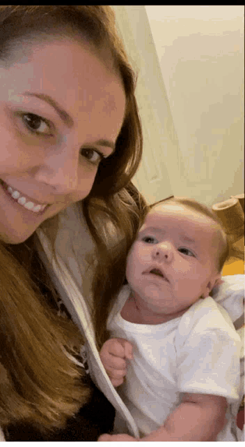 a woman holds a baby in her arms and smiles for the camera