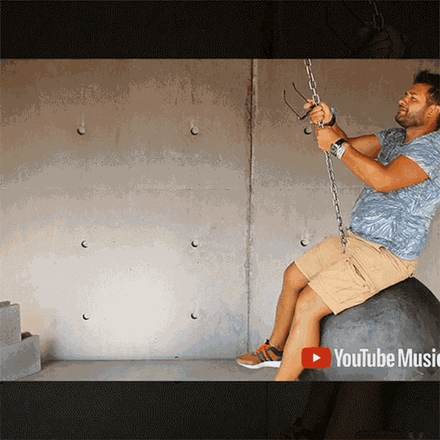 a video of a man sitting on a ball with a youtube music icon in the corner