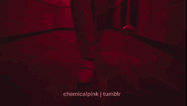 a person is walking down a hallway that is lit up in red .