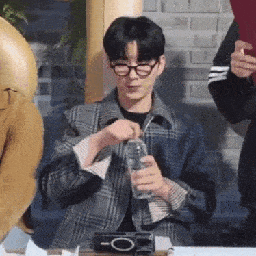 a man in a plaid jacket is holding a glass of water