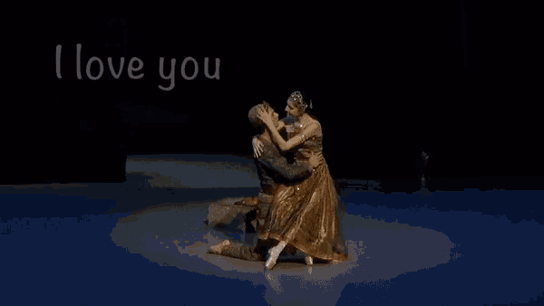 a man and a woman hugging on a stage with the words " i love you " above them