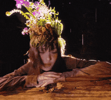 a woman with flowers on her head laying down