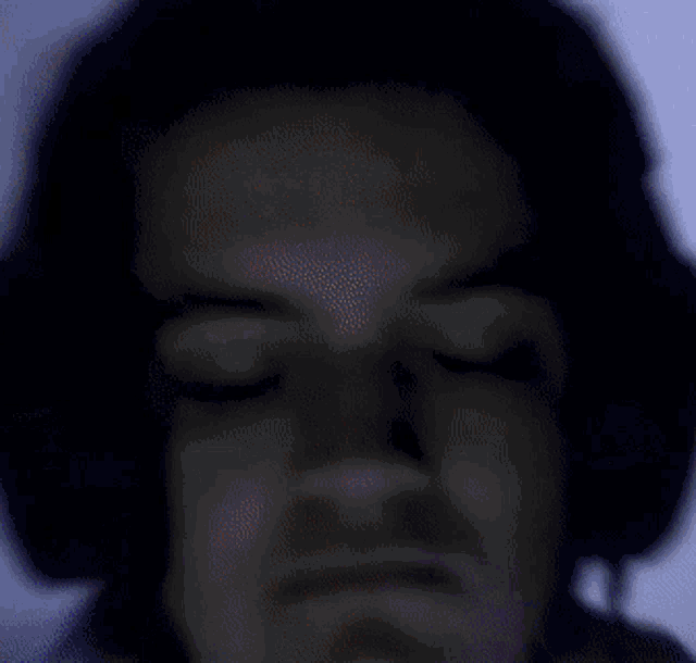 a man wearing headphones with his eyes closed looks at the camera