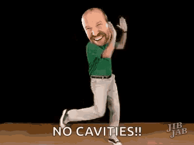a man in a green shirt is dancing on a wooden floor and says `` no cavities ! ''