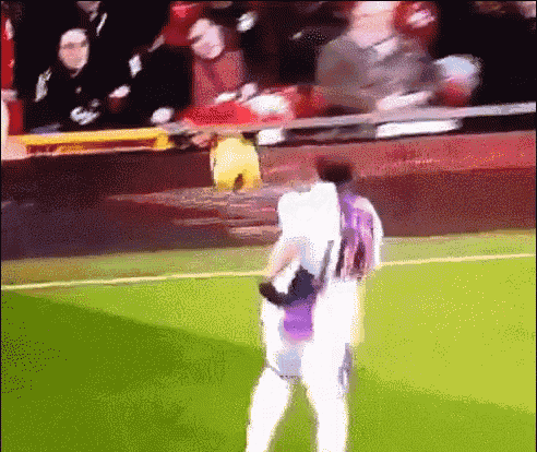 a soccer player wearing a purple jersey stands on the field