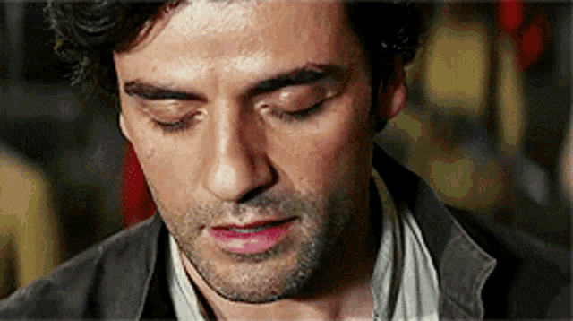 a close up of a man 's face with his eyes closed and a beard .