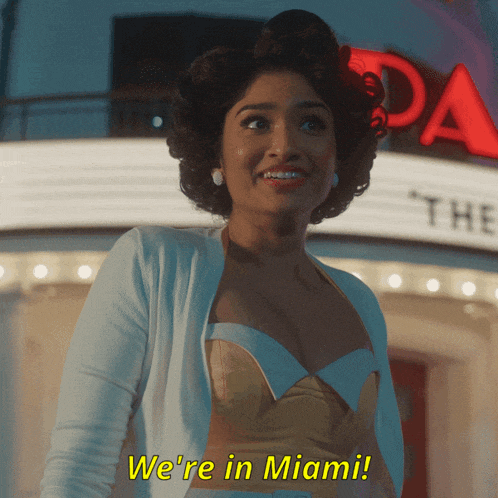 a woman says we 're in miami while standing in front of a building