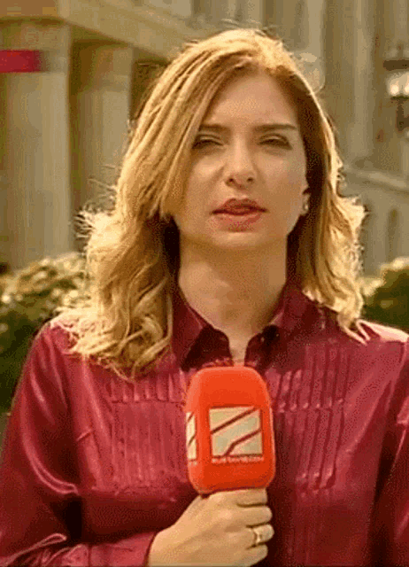 a woman in a red satin shirt is holding a red microphone with the letter z on it
