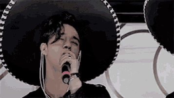 a man wearing a sombrero is singing into a microphone while wearing headphones .