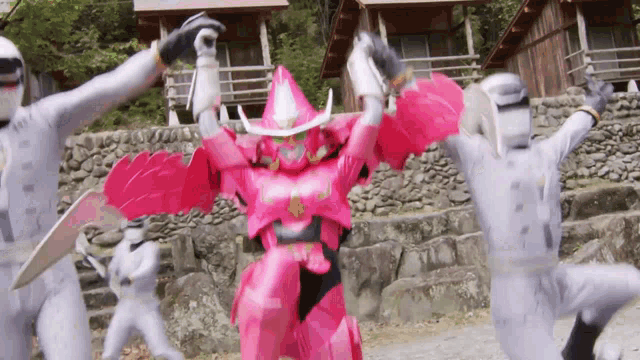 a group of ninja warriors are fighting a robot in a pink costume .