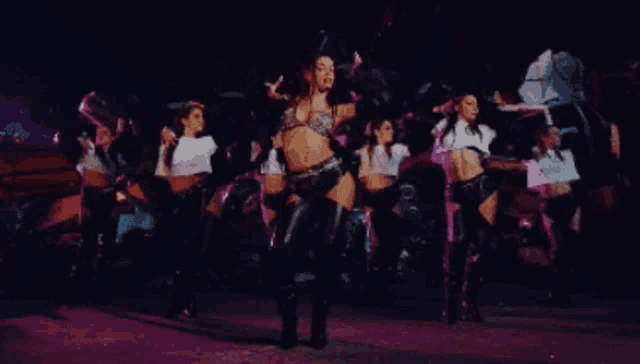 a group of women are dancing on a stage in a dark room
