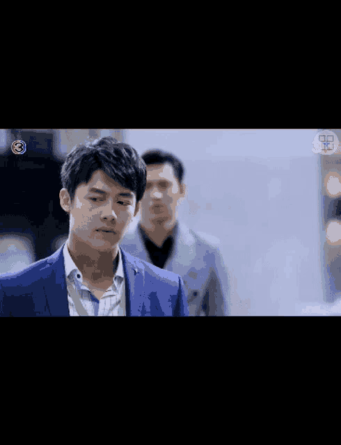 a man in a blue suit stands in front of another man