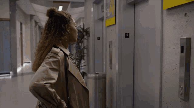 a woman standing in front of an elevator with the number 4