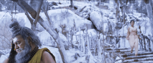 a man with a beard is talking on a cell phone in a snowy forest