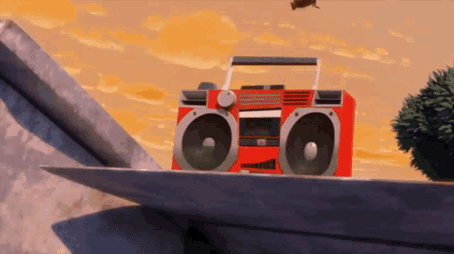 a red boombox sits on top of a cliff