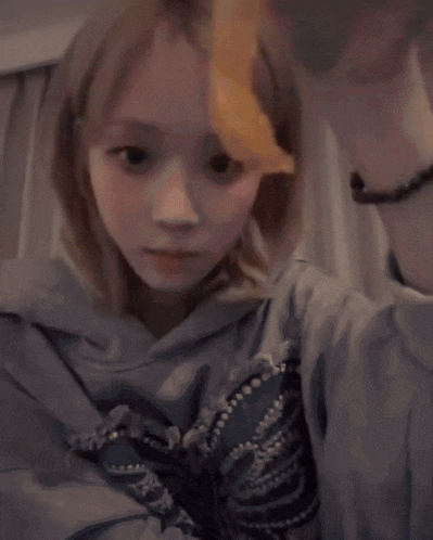 a girl wearing a blue sweatshirt with a butterfly on it looks at the camera