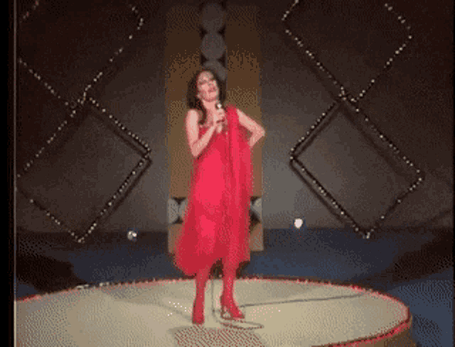 a woman in a red dress singing into a microphone on a stage