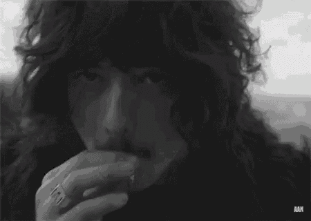 a black and white photo of a man smoking a cigarette .