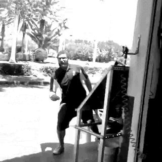 a black and white photo of a man standing on a table holding a ball .