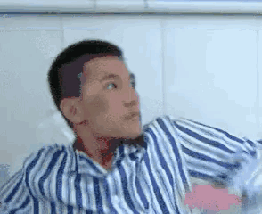 a man in a blue and white striped shirt is sitting in a hospital bed