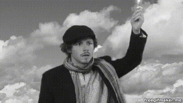 a man in a suit and scarf is holding a candle in his hand ..
